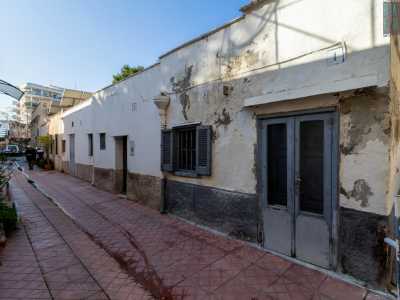 Ci guardiamo intorno e notiamo come la strada sia costituita da antichi e bassi edifici costruiti a fine 800. In origine abitazioni, nel corso del 900 furono poi adibiti a botteghe. La prima costruzione sulla nostra destra presenta una facciata bianca...
